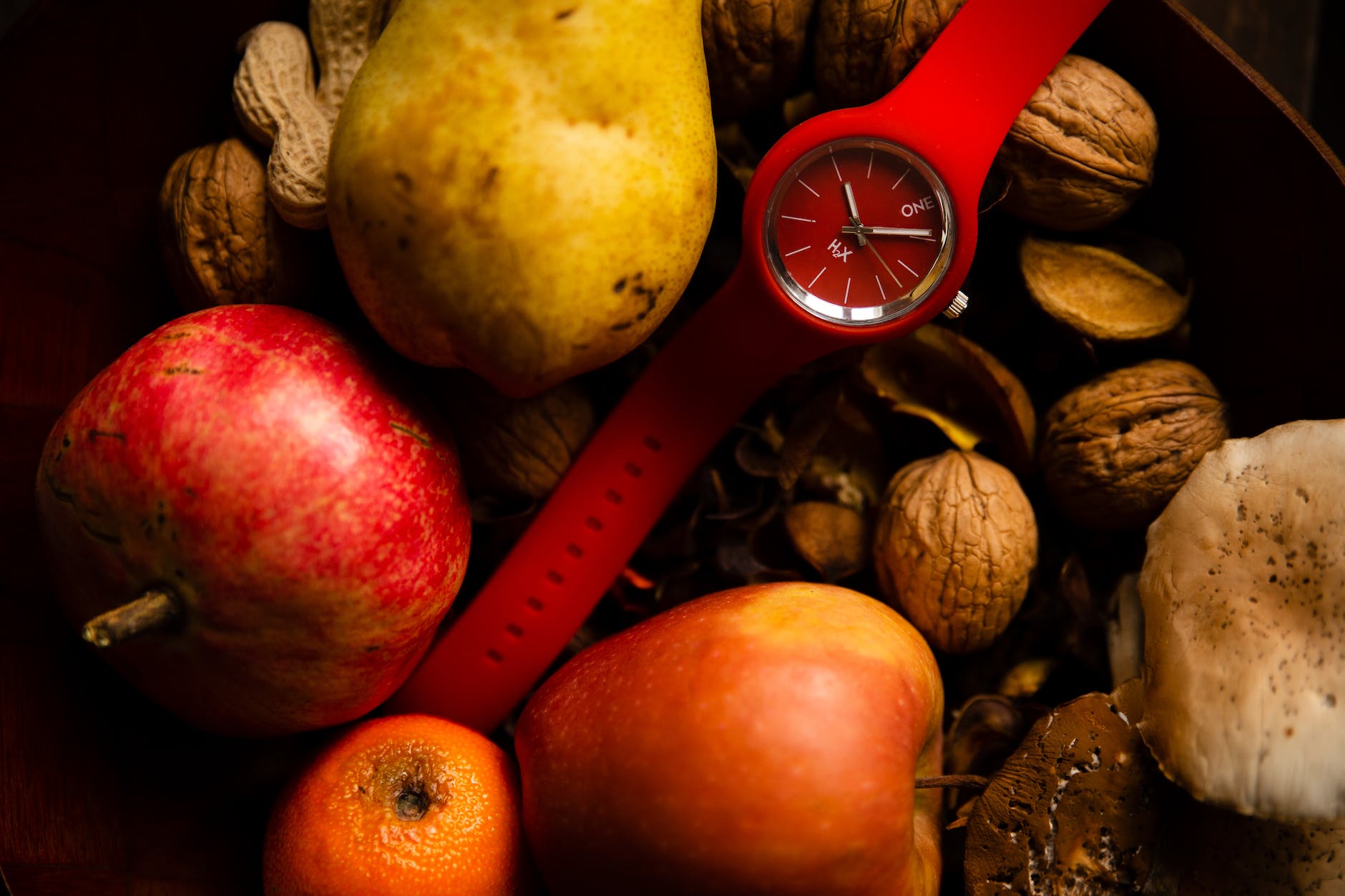 stylish red wristwatch placed in basket with fresh fruits and vegetables