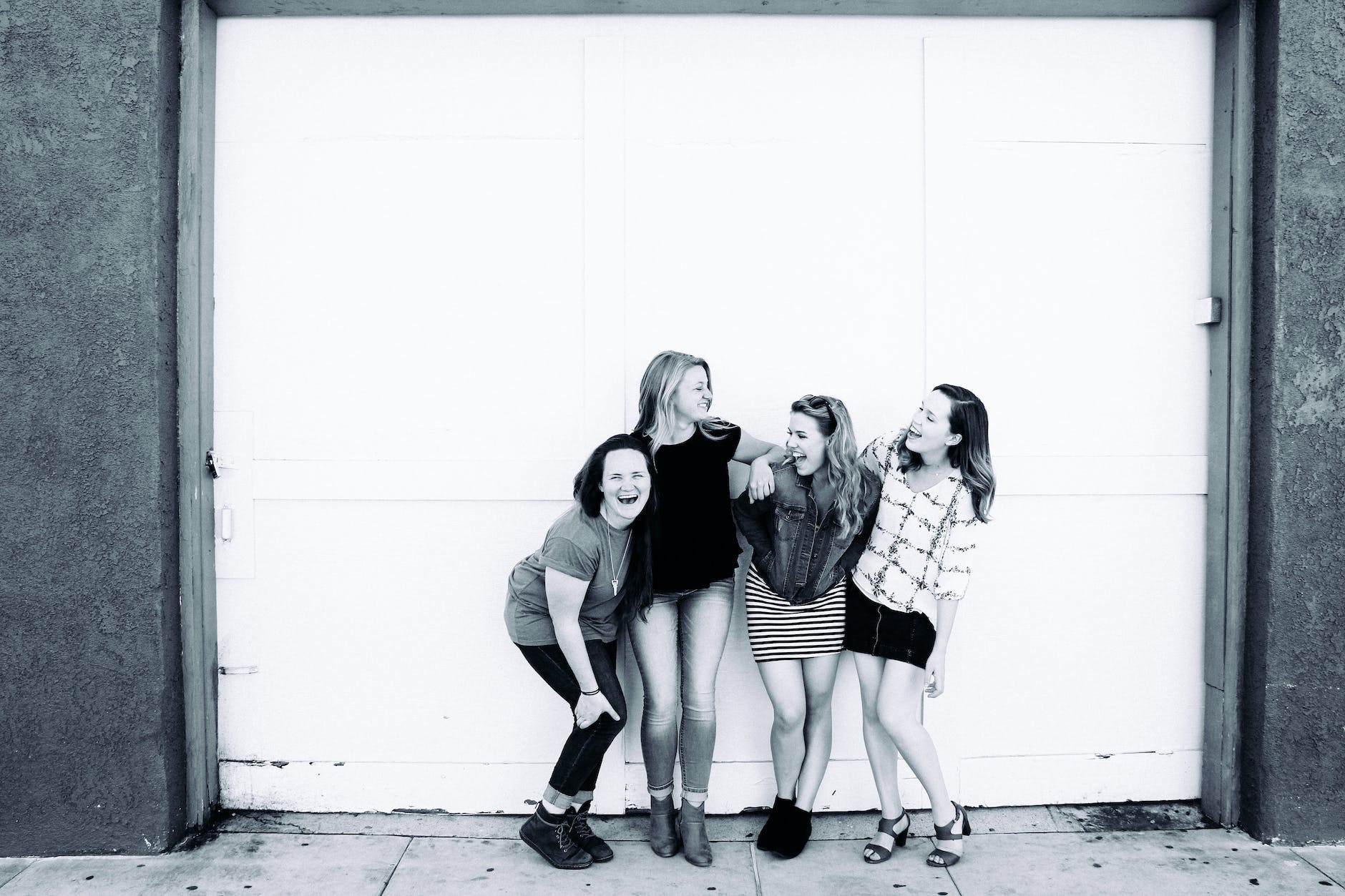 grayscale photography of four women wearing clothes